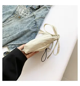 Detail shot of minimalist off-white nylon bucket bag with drawstring, casual crossbody style.