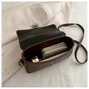 Detailed view of a retro brown leather cross-body shoulder bag showing interior capacity.