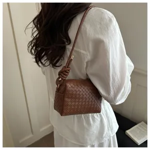 Woven shoulder crossbody bag in brown leather with stylish knotted handle and zip.