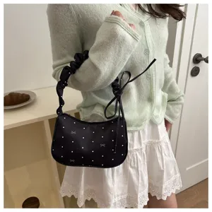 Detail shot of the black pleated underarm bag with white dots and cute bow patterns.