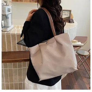 Detailed view of casual minimalist commuter tote bag in beige with brown shoulder straps.