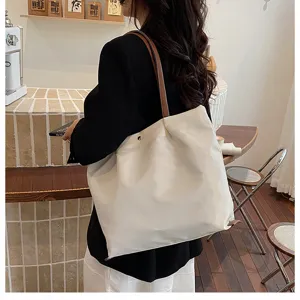 Detail view of casual white tote bag with brown straps, perfect for daily commuting and style.