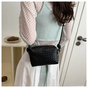 Close-up detail of black woven leather crossbody camera bag showcasing exquisite texture.