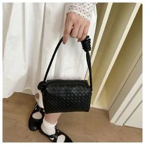 Black woven leather camera bag detail showcasing intricate texture and knotted top handle design.