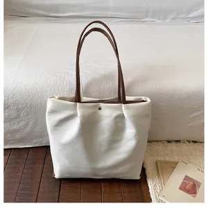 Detail view of a casual white tote bag with brown straps, minimalist design for daily commute.