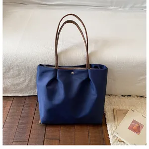Detail view of casual blue tote bag with brown handles, perfect for daily commute and travel.