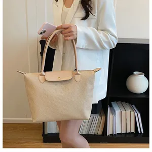 Beige woven tote bag with leather flap and handles, stylish commuter shoulder bag.
