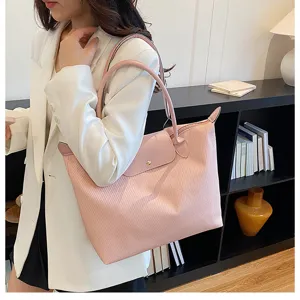 Detailed view of stylish pink nylon shoulder tote bag with leather flap and handles for women.