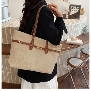 Detailed view of straw texture tote bag with brown leather straps and metal turn-lock closure.