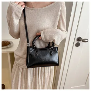 Close-up view of the black glossy retro handbag, showing the fine texture and handle details.