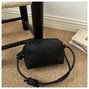 Woven leather crossbody camera bag, stylish black shoulder bag with chic knotted strap design.