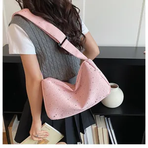 Gedetailleerd overzicht van de roze schoudertas met sterrenmotief gepresenteerd bij de planken.