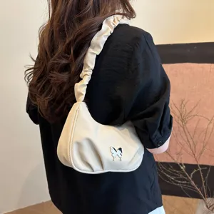 Detailed view of the chic beige ruched shoulder bag with cute butterfly detail, stylish underarm look.