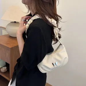 Chic pleated shoulder bag with a cute butterfly accessory, elegant white handbag for women.