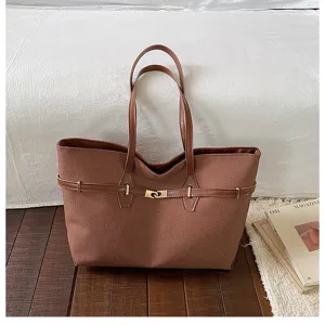 Detailed view of brown canvas tote bag featuring metal lock belt and double handles in cozy room