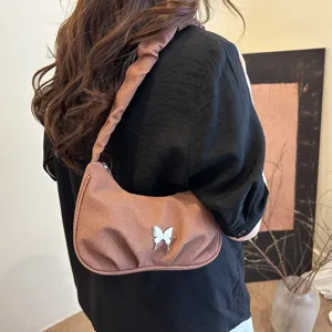 Stylish brown pleated shoulder bag for women with a cute butterfly accessory, trendy hobo handbag.