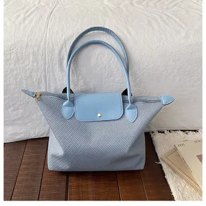 Chic light blue woven tote bag with leather flap and double handles for women daily commute.