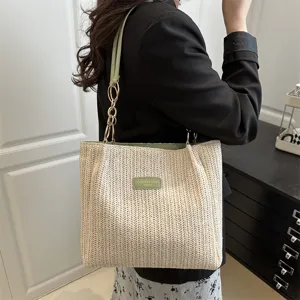 Woven straw shoulder tote bag with green chain strap, casual beach vacation style for women.