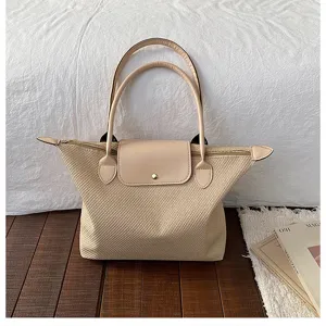 Beige woven tote bag with leather handles and flap closure, stylish commuter handbag.