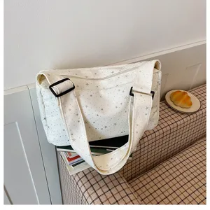 Gedetailleerd uitzicht op off-white canvas schoudertas met sterrenpatroon en brede band.