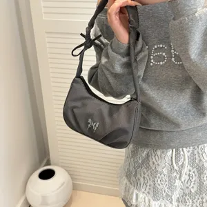 Detail view of the dark grey pleated underarm shoulder bag with a stylish metal butterfly decor.