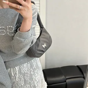 Detail shot of grey pleated shoulder bag with cute butterfly charm, casual everyday style.