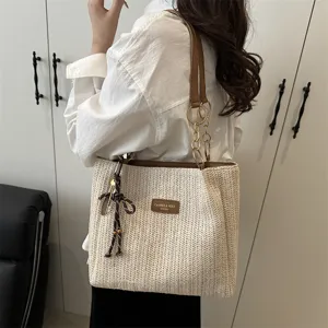 Detailed view of the stylish woven straw shoulder tote bag with chain strap and pendant.