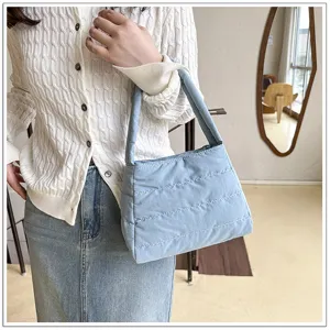 Detailed view of a light blue quilted nylon shoulder bag, stylish casual underarm handbag.