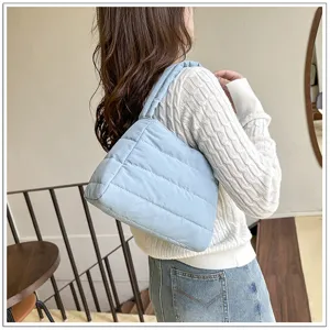 Details of the light blue quilted nylon shoulder bag worn by model, casual underarm style.