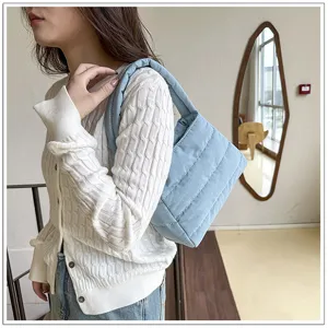 Detail view of a light blue quilted nylon underarm shoulder bag worn by model casually.