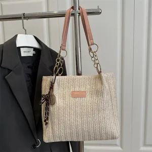Casual woven straw tote bag with pink leather straps and chain links, perfect for daily wear.