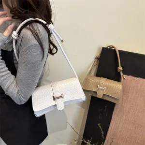 Vista detallada del elegante bolso de hombro tejido con cierre metálico y fina correa.