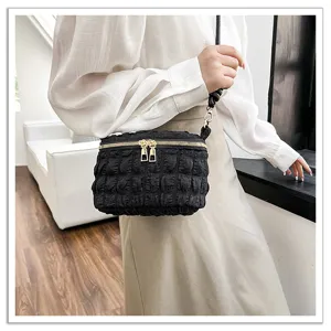 Black bubble pleated shoulder bag detail view, showing soft fabric texture and golden double zippers.