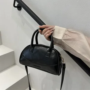 Black leather Boston handbag detail view, stylish small crossbody bag for women with top handles.