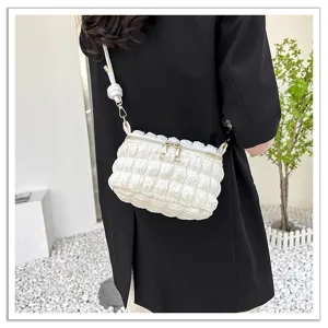 White pleated cloud crossbody bag detail shot, puffy shoulder bag with gold zippers.