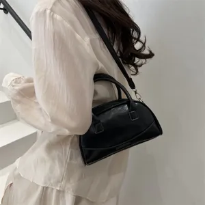 Detailed view of stylish black leather Boston handbag with top handles and shoulder strap.