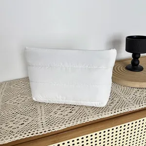 White quilted puffer clutch cosmetic bag detail shot in minimalist home decor scene