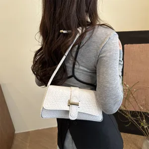 Vista detallada del elegante bolso de hombro blanco con motivo de cocodrilo y hebilla metálica.