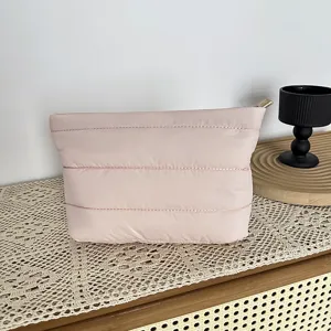 Detailed view of a minimalist pink quilted puffer clutch bag, stylish everyday cosmetic pouch.