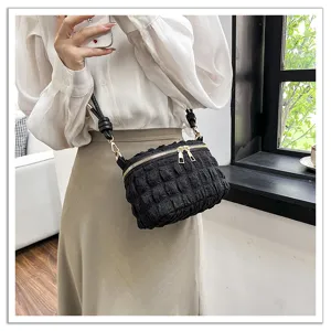 Black pleated cloud crossbody bag detail shot, showing soft texture and gold zipper hardware.