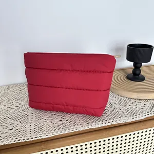 Red quilted cosmetic bag detailed closeup, soft puffer material handbag for daily use.