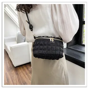 Black pleated mini crossbody bag worn by model, showcasing stylish cloud design and metal zippers.