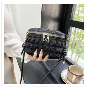 Detailed view of black pleated cloud mini crossbody bag featuring double metal zippers.
