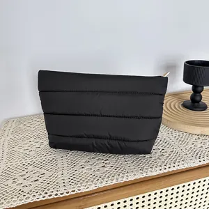Detailed shot of a stylish black quilted cosmetic bag with soft texture and gold zipper.