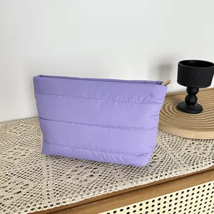 Purple quilted cosmetic pouch detail shot, soft padded travel makeup bag with minimalist style.