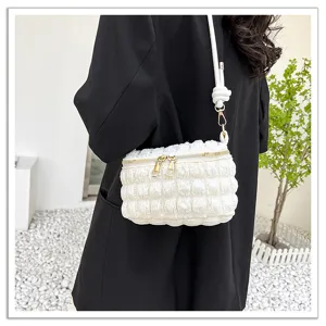 Close-up detail of the white ruched cloud bag showing golden zippers and shoulder strap.