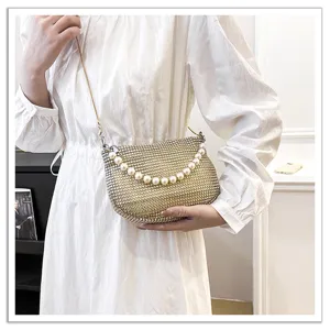 Detailed shot of glittering rhinestone evening bag with elegant pearl handle and sleek chain.