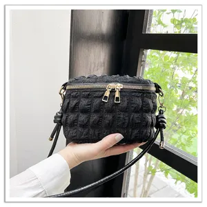 Closeup of black pleated cloud mini shoulder handbag with unique bubble texture and metal zippers.
