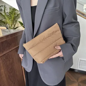 Detailed view of the stylish quilted puffer clutch bag in a soft casual brown tone design.