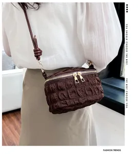 Detailed view of a stylish brown pleated puff shoulder bag with gold zippers and chic strap.